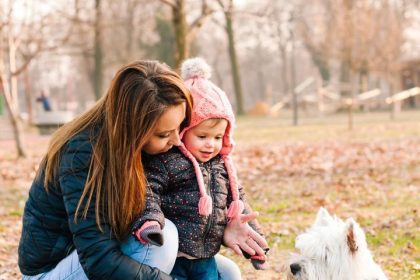 Beautiful little girl and her mother playing with a dog outdoor